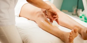 Young woman undergoing leg hair removal with honey